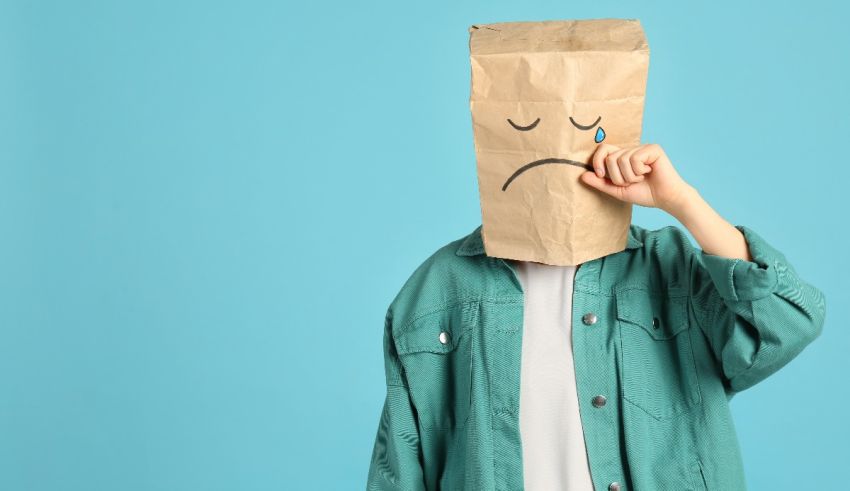 A man wearing a paper bag with a sad face on it.